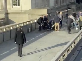 People hold down a man who had stabbed a number of people, on the London Bridge, in London, Britain, November 29, 2019 in this still image obtained from a social media video. HAND LUGGAGE ONLY via REUTERS THIS IMAGE HAS BEEN SUPPLIED BY A THIRD PARTY. MANDATORY CREDIT. NO RESALES. NO ARCHIVES. ORG XMIT: LNDB001