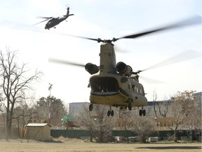 The last Canadians involved in the NATO training mission in Afghanistan (CCTM-A) fly off on an American Chinook helicopter, escorted by an American Blackhawk helicopter on March 12, 2014 as they leave the International Security Assistance Force (ISAF) headquarters in Kabul, Afghanistan.