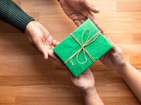 A woman hands over a gift to her friend to celebrate the holidays.