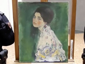 Italian police stand next to what they say is a masterpiece by Austrian artist Gustav Klimt "Portrait of a Lady" that was stolen in 1997 and was found hidden in an outside wall of an Italian gallery, in Piazcenza, Italy December 10, 2019 in this still image taken from a video.