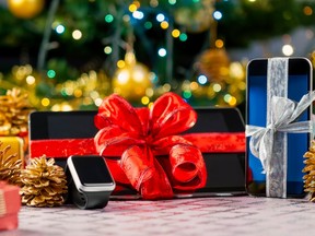 Tablet pc, smartphone and smartwatch with gifts and decorations in front of Christmas tree.
