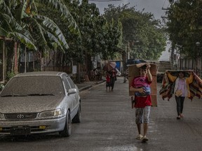 Residents walk along a road covered in ash mixed with rainwater as Taal Volcano erupts on Sunday in Talisay, Batangas province, Philippines.