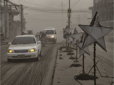 Motorists drive through a road covered in volcanic ash from Taal Volcano's eruption on January 13, 2020 in Lemery, Batangas province, Philippines. The Philippine Institute of of Volcanology and Seismology raised the alert level to four out of five, warning that a hazardous eruption could take place anytime, as Manila's international airport suspended flights and authorities began evacuating tens of thousands of people from the area.