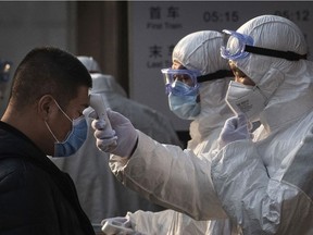 A Chinese health worker checks the temperature of a woman entering a subway station during the Chinese New Year and Spring Festival on January 25, 2020 in Beijing, China.