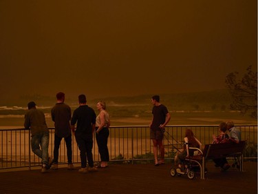 Residents look out over the beach as thick smoke covers the skyline on January 04, 2020 in Tuross Head, Australia. A state of emergency has been declared across NSW with dangerous fire conditions forecast for Saturday, as more than 140 bushfires continue to burn. There have been eight confirmed deaths in NSW since Monday 30 December. 1365 homes have been lost, while 3.6 million hectares have been burnt this fire season.