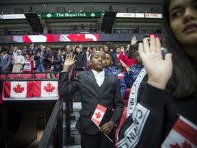 Ahmed Mohammed, 11, holds his hand up while taking the oath of citizenship during Saturday's ceremony at Canadian Tire Centre before the NHL game between the Senators and visiting Calgary Flames.