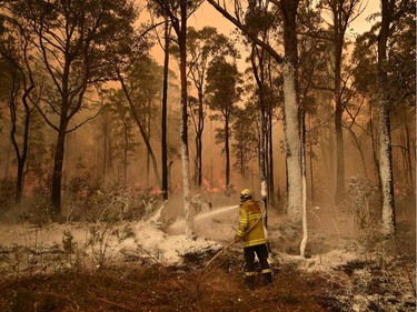 A firefighter sprays foam retardant on a back burn ahead of a fire front in the New South Wales town of Jerrawangala on January 1, 2020. - A major operation to reach thousands of people stranded in fire-ravaged seaside towns was under way in Australia on January 1 after deadly bushfires ripped through popular tourist spots and rural areas leaving at least eight people dead.