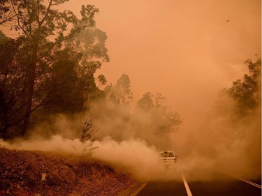 Firefighters tackle a bushfire in thick smoke in the town of Moruya, south of Batemans Bay, in New South Wales on January 4, 2020. - Up to 3,000 military reservists were called up to tackle Australia's relentless bushfire crisis on January 4, as tens of thousands of residents fled their homes amid catastrophic conditions.