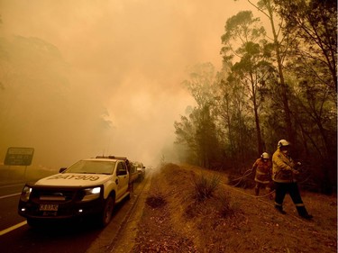 Firefighters tackle a bushfire in thick smoke in the town of Moruya, south of Batemans Bay, in New South Wales on January 4, 2020. - Up to 3,000 military reservists were called up to tackle Australia's relentless bushfire crisis on January 4, as tens of thousands of residents fled their homes amid catastrophic conditions.