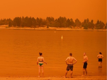 Residents take a dip to cool down at Lake Jindabyne, under a red sky due to smoke from bushfires, in the town of Jindabyne in New South Wales on January 4, 2020. - Up to 3,000 military reservists were called up to tackle Australia's relentless bushfire crisis on January 4, as tens of thousands of residents fled their homes amid catastrophic conditions.
