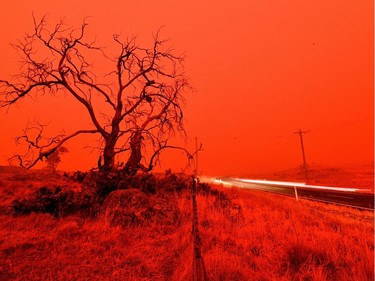 A long exposure picture shows a car commuting on a road as the sky turns red from smoke of the Snowy Valley bushfire on the outskirts of Cooma on January 4, 2020. - Up to 3,000 military reservists were called up to tackle Australia's relentless bushfire crisis on January 4, as tens of thousands of residents fled their homes amid catastrophic conditions.