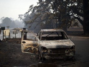 A burnt vehicle is seen on Quinlans street after an overnight bushfire in Quaama in Australia's New South Wales state on January 6, 2020. - Reserve troops were deployed to fire-ravaged regions across three Australian states on January 6 after a torrid weekend that turned swathes of land into smouldering, blackened hellscapes.