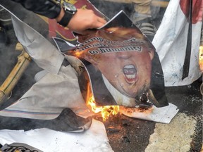 People burn a poster representing US President Donald Trump (C) to protest against the US authorities for the killing of Iranian commander Qasem Soleimani in Iraq, during a demonstration near the US embassy in New Delhi on January 7, 2020. - A US drone strike killed top Iranian commander Qasem Soleimani at Baghdad's international airport on January 3, dramatically heightening regional tensions and prompting arch enemy Tehran to vow "revenge". (Photo by Prakash SINGH / AFP)