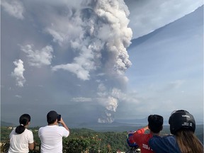 People take photos of a phreatic explosion from the Taal volcano as seen from the town of Tagaytay in Cavite province, southwest of Manila, on January 12, 2020.