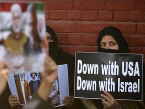 People hold placards to protest against the US military action for the killing of the top Iranian general Qasem Soleimani.