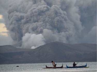 Residents living along Taal lake catch fish as Taal volcano erupts in Tanauan town, Batangas province south of Manila on January 14, 2020. - Taal volcano in the Philippines could spew lava and ash for weeks, authorities warned on January 14, leaving thousands in limbo after fleeing their homes fearing a massive eruption.