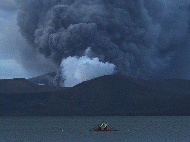 Residents living along Taal lake catch fish as Taal volcano erupts in Tanauan town, Batangas province south of Manila on January 14, 2020. - Taal volcano in the Philippines could spew lava and ash for weeks, authorities warned on January 14, leaving thousands in limbo after fleeing their homes fearing a massive eruption.