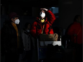 Two passengers wearing masks arrive at Beijing International Airport on January 20, 2020, ahead of the Lunar New Year. - China is in the midst of its annual travel rush as millions head to their hometowns to enjoy a week-long holiday to welcome in the Lunar New Year of the Rat.