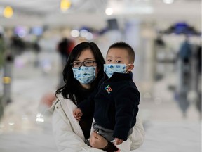 A woman and a child wearing protective masks walk toward check-in counters at Daxing international airport in Beijing on January 21, 2020. - The death toll from a new China virus that is transmissible between humans rose to six, the mayor of Wuhan said in an interview with state broadcaster CCTV on January 21, as the World Health Organization said it would consider declaring an international public health emergency over the outbreak.