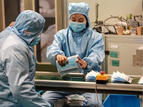 This photo taken on January 26, 2020 shows workers producing facemasks at a factory in Yangzhou in China's eastern Jiangsu province, to support the supply of medical materials during a deadly virus outbreak which began in Wuhan. - At least 81 people have died since the new strain of coronavirus emerged in China's Wuhan, and millions are now under an effective quarantine, with all flights in and out of the city grounded and a ban on Chinese tour groups domestically and abroad. (Photo by STR / AFP) / China OUT