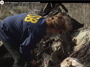 This still image taken from a video was released Tuesday by the National Transportation Safety Board. It shows an NTSB official inspecting the remains of the helicopter that crashed Sunday near Calabasa, Calif., killing all nine people on board.