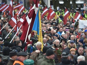 Veterans of the Latvian Legion, a force that was commanded by the German Nazi Waffen SS during WWII, and their sympathizers carry flowers as they walk to the Monument of Freedom in Riga, Latvia on March 16, 2016 to commemorate a key 1944 battle in their ultimately failed attempt to stem a Soviet advance. Jewish groups, Moscow and some in Latvia's ethnic-Russian community see the parade as glorifying Nazism because the Legion, founded in 1943, was commanded by Germany's Waffen SS, the armed wing of the Nazi party's Schutzstaffel SS (Protective Squadron). / AFP / afp / Ilmars Znotins