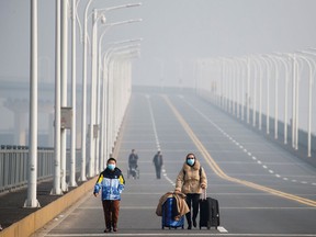 A mother and her son arrive from Hubei province at a checkpoint at the Jiujiang Yangtze River Bridge in Jiujiang, Jiangxi province, China, as the country is hit by an outbreak of a new coronavirus, January 31, 2020.