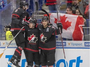 Canada's Connor McMichael, centre, celebrates with teammates Liam Foudy, left, and Joe Veleno, right, after scoring a goal in the second period of Thursday's game against Slovakia.