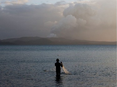 A man catches fish as the Taal Volcano continues to erupt in Talisay, Batangas, Philippines, January 14, 2020.