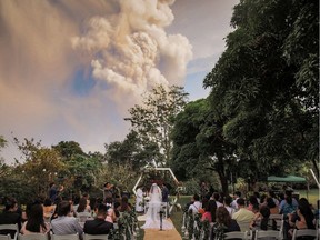 People attend a wedding ceremony as Taal Volcano sends out a column of ash in the background in Alfonso, Cavite, Philippines, January 12, 2020, in this image obtained from social media.