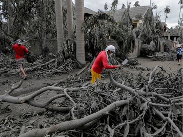 A worker chops off fallen branches in a resort blanketed with volcanic ash in Talisay, Batangas, Philippines, January 14, 2020.