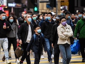 Pedestrians wearing face masks cross a road during a Lunar New Year of the Rat public holiday in Hong Kong on Jan. 27, 2020.