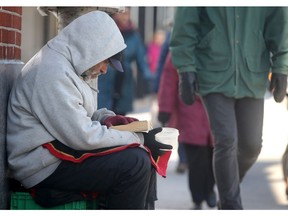 A homeless man begs for money near City Hall .