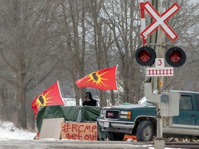 A man smokes at the site of a rail stoppage on Tyendinaga Mohawk Territory, as part of a protest against British Columbia's Coastal GasLink pipeline, in Tyendinaga, Ontario, Feb. 16, 2020.