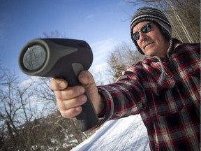 Almonte resident Bruce Matheson uses a radar gun to clock snowmobile riders on the Ottawa Valley Rail Trail where it passes through town.