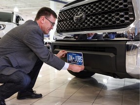 MPP Bill Walker holds up a new Ontario commercial vehicle licence plate on the front bumper of a truck. All licence plates issued in Ontario will be modelled off this new plate design starting Feb. 1, 2020, according to a news release from Walker's office.