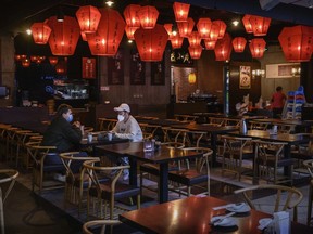 Chinese men wear protective masks as they sit in a nearly empty restaurant in the food court of a usually busy shopping mall on February 22, 2020 in Beijing, China.