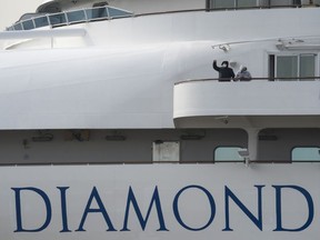 Passengers are seen on a cabin balcony of the Diamond Princess cruise ship docked at Daikoku Pier on Wednesday in Yokohama, Japan. The cruise ship, while being resupplied, remains in quarantine after a number of the 3,700 people on board were diagnoses with coronavirus. The number of confirmed cases have climbed to 175 as Japanese authorities continue treating people on board.