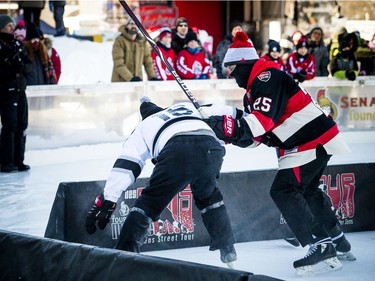 The Ottawa Senators Alumni and NHL Alumni held a shinny game at the Rink of Dreams in front of City Hall Saturday, February 8, 2020, part of the Home Town Hockey Tour. Sens Alumni Chris Neil pushes Shawn Rivers into the very short boards.   Ashley Fraser/Postmedia
