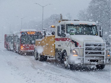 An OC Transpo bus gets towed after getting stuck on Carling Avenue during a heavy snowfall in Ottawa. February 27, 2020.