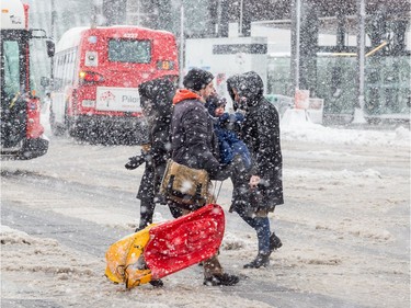 A man and young child struggle to cross Scott Street at Holland Avenue during a heavy snowfall in Ottawa. February 27, 2020.