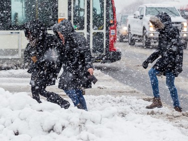 Women navigate Scott Street during a heavy snowfall in Ottawa. February 27, 2020.
