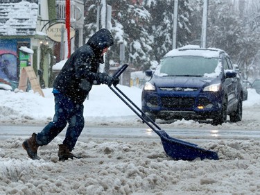 A man really has to put his back into it while clearing snow in front of Starbucks on Bank Street Thursday.