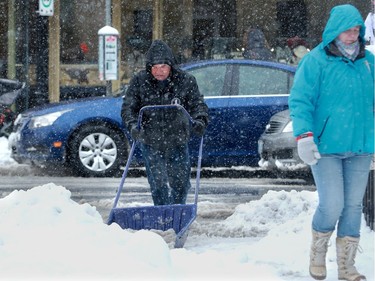 A man really has to put his back into it while clearing snow in front of Starbucks on Bank Street Thursday.