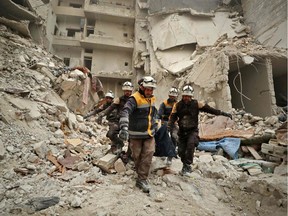 Rescue workers known as the White Helmets carry away the body of a victim found amidst the rubble of a building, hit during an air strike by pro-regime forces on the rebel-held town of Ariha in the northern countryside of Syria's Idlib province, on February 5, 2020.