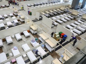 This photo taken on February 5, 2020 shows medical staff members and workers setting up beds as they prepare to accept patients displaying mild symptoms of novel coronavirus infection at an exhibition centre converted into a hospital in Wuhan in China's central Hubei province.