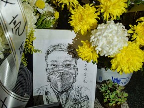 This photo taken on Feb. 7, 2020 shows a photo of the late ophthalmologist Li Wenliang with flower bouquets. Li, who was punished after raising the alarm about the new coronavirus, died that day after being infected by the pathogen.