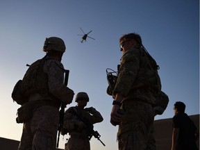 US Marines and Afghan Commandos stand together as an Afghan Air Force helicopter flies past during a combat training exercise at Shorab Military Camp in Lashkar Gah in August 2017.