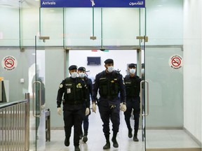 Kuwaiti policemen wearing protective masks wait at Sheikh Saad Airport in Kuwait City, on February 22, 2020, before transferring Kuwaitis arriving from Iran to a hospital to be tested for coronavirus. (Photo by YASSER AL-ZAYYAT / AFP)