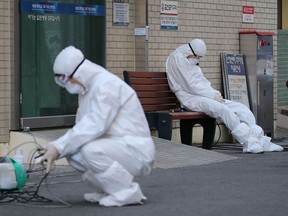 A medical worker wearing protective gear takes a rest as he waits for ambulances carrying patients infected with the COVID-19 coronavirus at an entrance of a hospital in Daegu on Sunday. - South Korea raised its alert on the coronavirus to the highest level on February 23 after reporting three more deaths and 169 new infections.